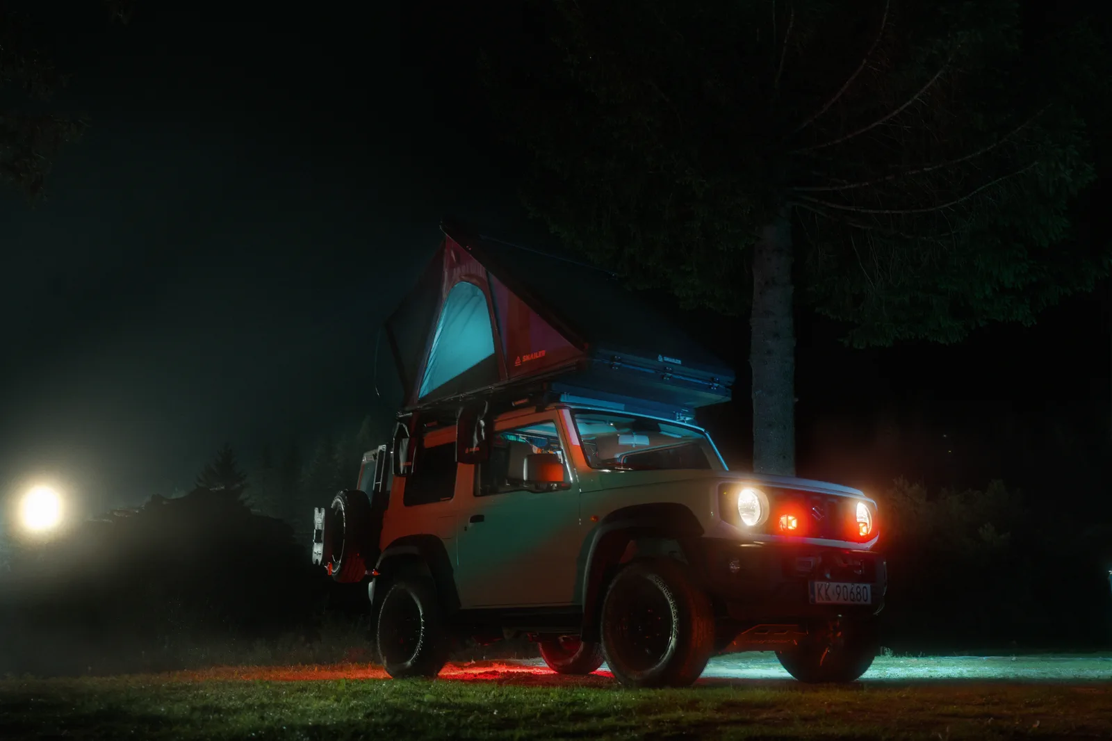 Véhicule tout-terrain équipé d’une tente de toit SNAILER éclairée la nuit