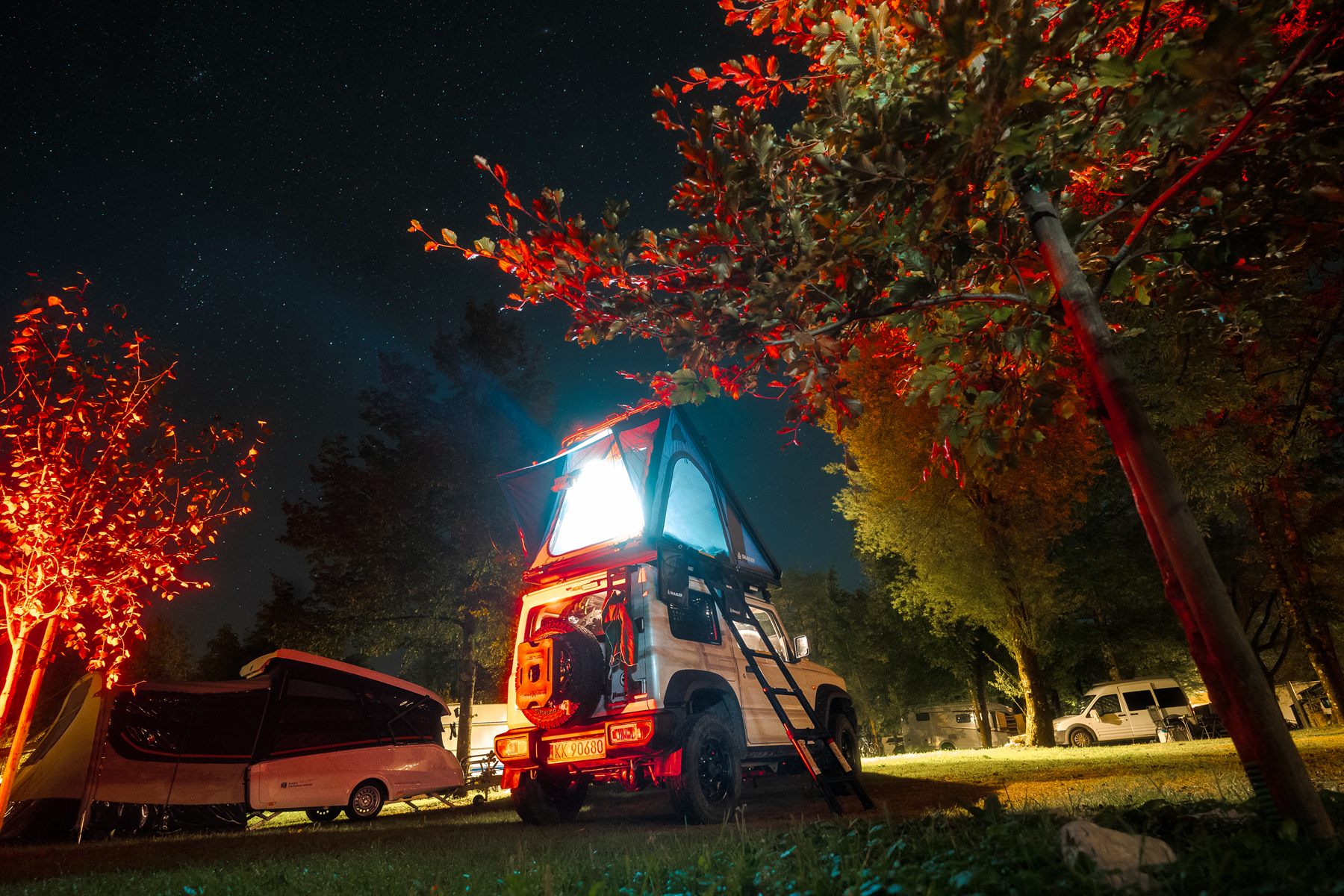 Tente de toit Snailer éclairée dans un camping la nuit