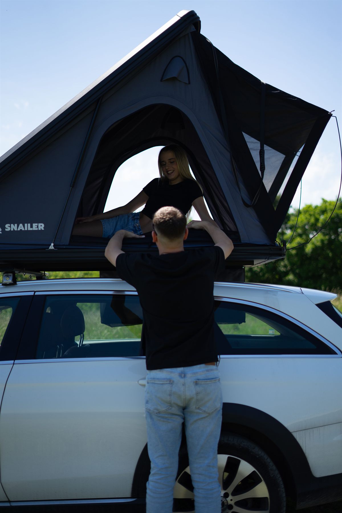 Homme ouvrant une grande tente de toit Snailer sur le toit d’une voiture